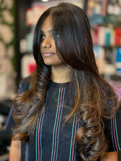 This image showcases a beautiful balayage with warm, caramel tones on a layered cut. The color placement is designed to look natural and grow out gracefully.