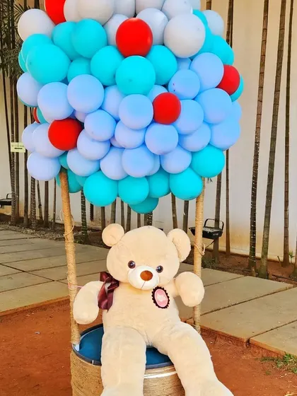 A giant teddy bear sitting in a hot air balloon basket makes for an adorable and whimsical photo prop at a child's party.