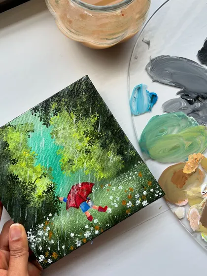 Holding the rainy day painting, with my paint palette in the background. It shows the colors I mixed to get the perfect shades of green.