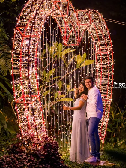 Framed by a giant heart made of countless fairy lights. This is a classic romantic shot that beautifully captures the couple's joy and the magical ambiance of the night.