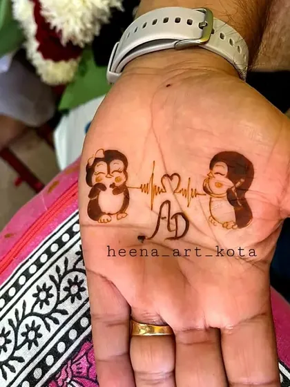 A cute and minimal design for the groom's palm, featuring two penguins, the couple's initials, and a heartbeat line connecting them.