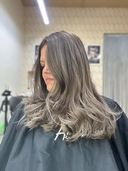 A closer look at a beautiful ash balayage. Notice the seamless transition from the natural root color to the cool, ashy ends, styled with soft waves.
