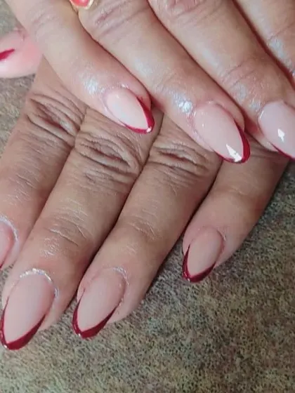 An elegant and sophisticated French manicure using a deep maroon for the tips on almond-shaped nails. The sharp V-shape gives it a very modern and chic feel.