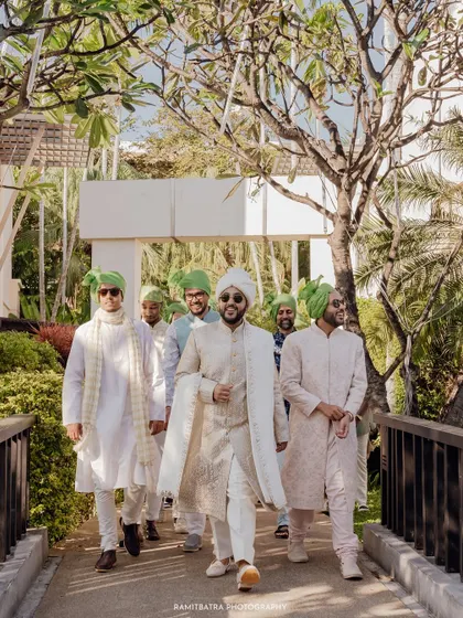 The groom and his groomsmen make a stylish entrance, walking across a bridge at the resort.