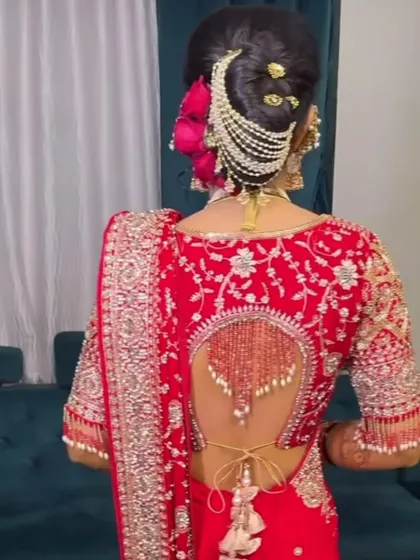 The back view of a bride, showcasing the detailed blouse design and an intricate hairstyle with a pearl accessory.