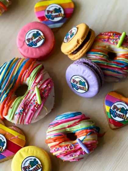 A variety of our Pride Month treats, including rainbow donuts, heart shaped cookies, and custom printed macarons.