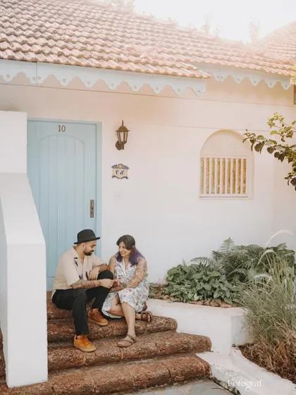 A candid moment of a couple sitting on the steps of a Goan villa, sharing a quiet conversation and a smile.