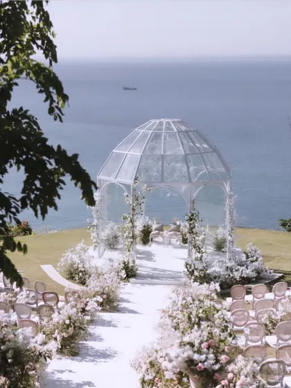 A breathtaking view of the glasshouse mandap in Bali, set against the vast ocean. The all-white floral decor and transparent structure created a feeling of being on top of the world.