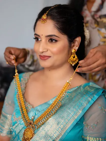 A behind the scenes moment, getting the bride ready. This shot shows the soft, natural makeup base and defined eyes before the final jewellery is placed.