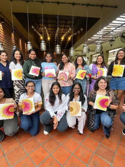 The whole group from a texture painting workshop, kneeling with their finished sunflower artworks.