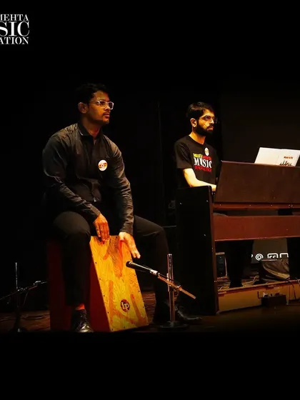 Two of our students perform on stage with their teacher. We provide a complete support system, including professional accompaniment, to ensure our students shine during their performances.