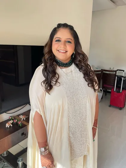 A full-length view of this chic and modern look. The cream-colored kaftan is the perfect canvas for the pop of green in the makeup.