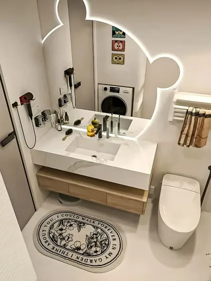 A fun and functional family bathroom with a Mickey Mouse-shaped backlit mirror and a well-organized vanity area.