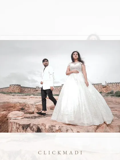 A dramatic pre-wedding portrait set against the stunning cliffs and river of Gandikota, often called the Grand Canyon of India. The bride's white gown flows beautifully in the wind.