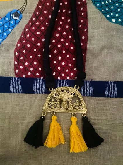 The third piece from the Dokhra collaboration, featuring a black cord with playful yellow and black tassels that highlight the traditional motifs in the pendant.
