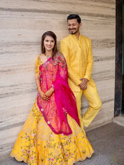 A full-length portrait of the couple. The bride's vibrant lehenga and soft makeup create a beautiful contrast.