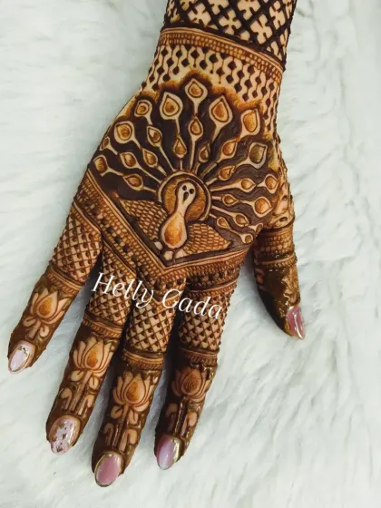 A bold and beautiful peacock design on the back of the hand. The fanned-out tail feathers are filled with detailed patterns, and the lotus motifs on the fingers add to the traditional feel.