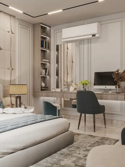 A sophisticated bedroom design that incorporates a study desk and vanity area. The wall features a combination of padded panels and classic molding.