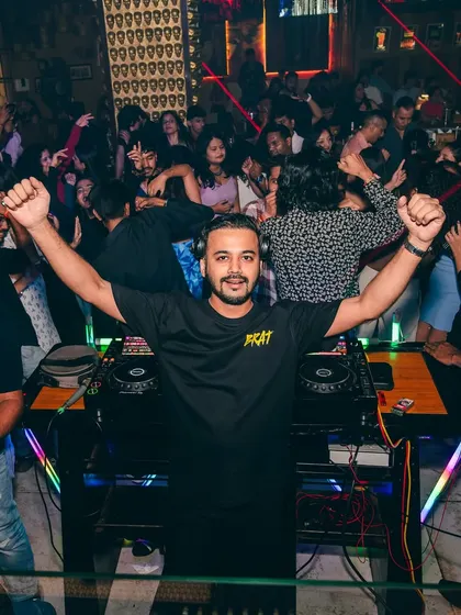 Both hands in the air, celebrating a massive beat drop with the audience.