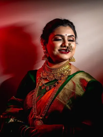 A dramatic bridal portrait using creative lighting to highlight the bride's features and the rich texture of her traditional saree and gold jewelry.