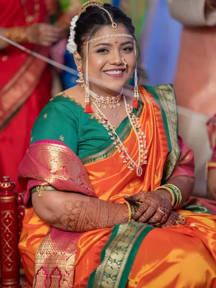 The smile says it all. This bride is glowing in a traditional Kashibai-style Nauvari, looking like a dream in a vibrant orange and green combination for her wedding day.