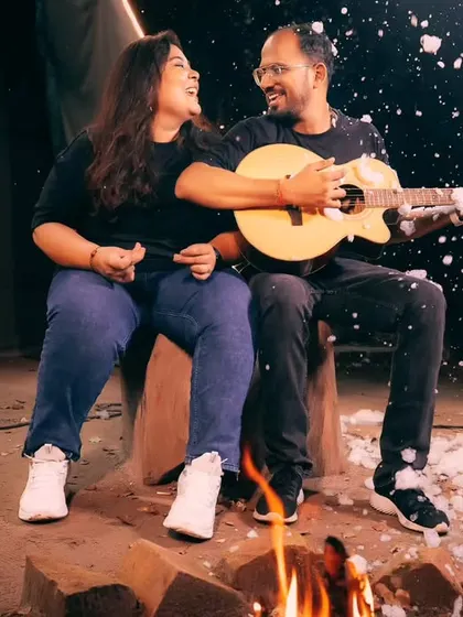 A fun and musical pre-wedding setup, with the couple enjoying a campfire, a guitar, and a playful snow effect for a memorable and unique photo.