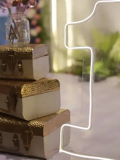 A close-up of the props from a fairy-themed party, including a neon '1' and miniature vintage suitcases. These small details enhance the overall magical feel.