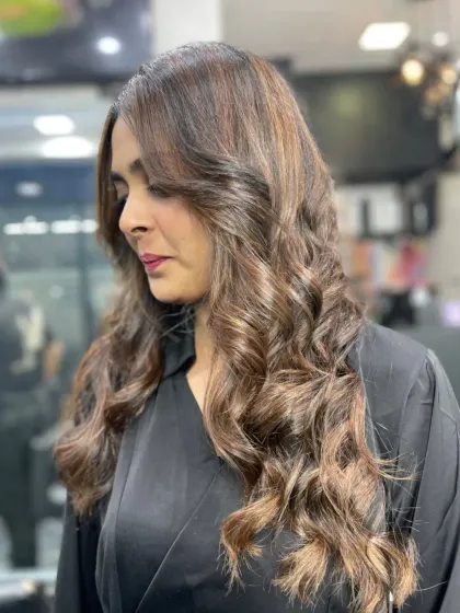 A sophisticated look with medium-length hair styled in perfect, glossy curls with subtle highlights.