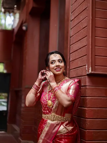 A candid moment of the bride adjusting her earring. Her makeup looks flawless, and her smile is infectious.