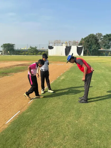 A coach inspects the pitch with two young captains before the start of a match, teaching them about reading the conditions.