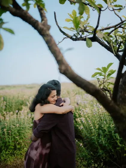A sweet embrace captured from behind a tree, adding a sense of intimacy to this pre-wedding photo.