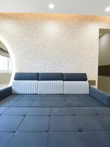 This multifunctional room serves as both an entertainment area and a guest bedroom. The dark blue sofa bed is a practical and stylish solution for accommodating guests.