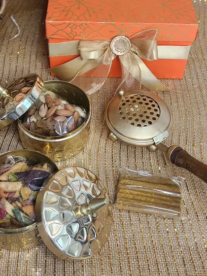 A traditional Diwali gift set featuring brass containers filled with dry fruits and an ornate brass dhoop holder. It's a classic gift that embodies the spirit of the festival.