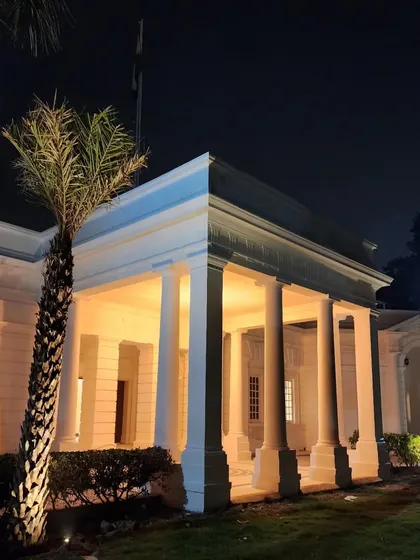 The classical architecture is beautifully complemented by our landscape lighting design, which casts a warm glow on the columns and surrounding greenery.