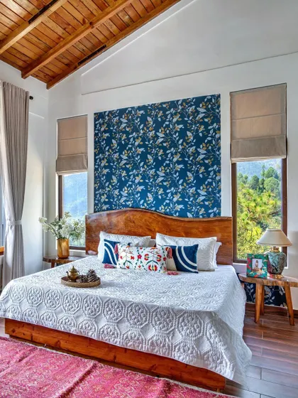 Another angle of the master bedroom in Mukteshwar, highlighting the custom wooden bed and the expansive windows that offer panoramic views of the surrounding hills.