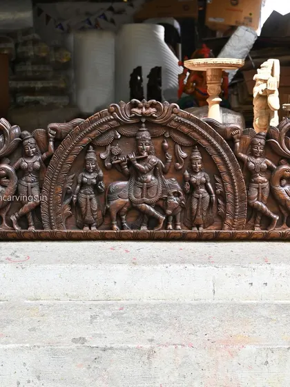 Our 54-inch Kirthi Mukh arch panel frames a serene scene of Lord Krishna playing his flute. The single-tone wood finish emphasizes the graceful forms of Krishna, his attendants, and the surrounding peacocks.