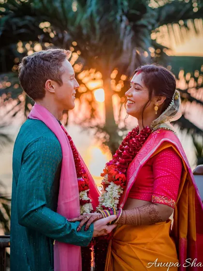 A stunning golden hour portrait. The setting sun behind the couple creates a warm, romantic glow, perfectly highlighting their happy expressions.