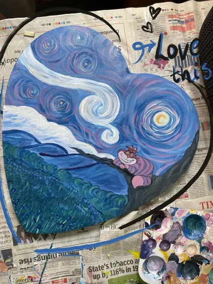 A work-in-progress shot of a large, heart-shaped wood panel I painted with a Starry Night and Cheshire Cat mashup.