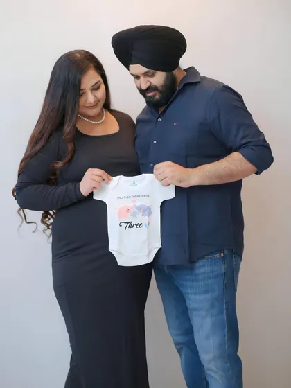 Announcing the next chapter for their family of two. The couple holds up a "We're expecting" onesie, a sweet and simple way to share their happy news through their maternity photos.