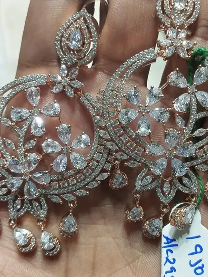 Large, round chandbali earrings in rose gold polish, studded with American diamonds. The floral pattern is very intricate and beautiful.