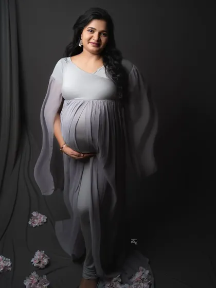 A beautiful, direct-to-camera pose showcasing the elegant drape of the grey gown. This is a timeless and classic maternity portrait.