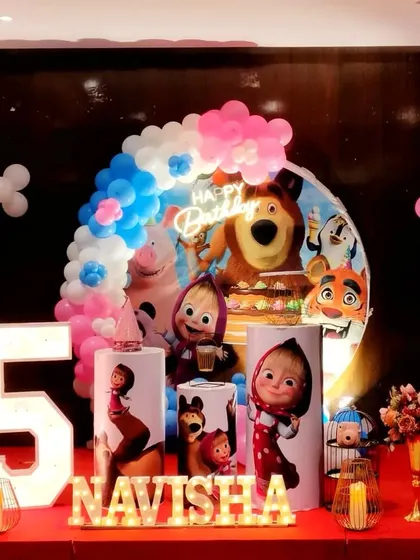 A fun Masha and the Bear theme for a 5th birthday, with a large backdrop and character-themed pedestals.