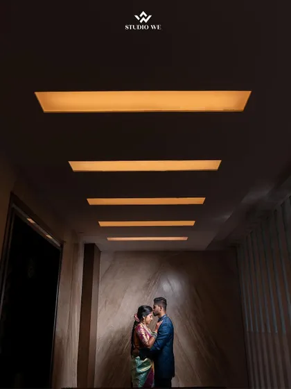 A beautifully composed shot of a couple in a hallway, using the ceiling lights to create leading lines. This architectural approach to a portrait is both modern and artistic.