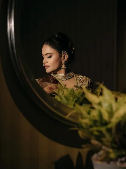 A moment of quiet reflection. The mirror captures the soft yet defined makeup, with contoured cheeks and beautifully shaped brows that frame her face perfectly.