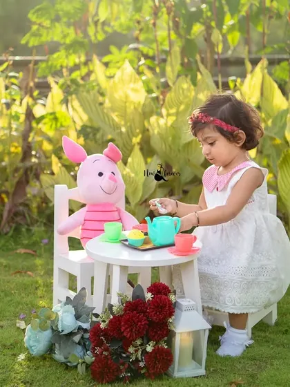 Pouring tea for her friend Piglet. This imaginative play during her second birthday shoot shows her sweet and caring personality.