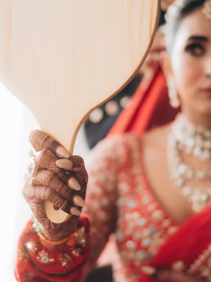 A creative shot using a hand mirror, focusing on the bride's hand and mehndi. I love finding unique perspectives to tell the story of the day.
