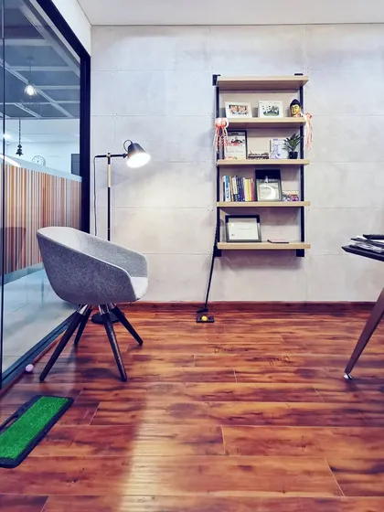 The director's cabin, which combines professional function with personal touches. The design includes a sleek desk, comfortable seating for guests, and even a personal golf putting green, reflecting a modern leadership style.