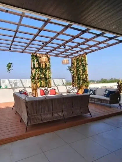 For Rishab Girias at Swiss Town, we designed this expansive terrace lounge. It features a glass pergola for an open feel, a large WPC deck for seating, and vertical gardens on bamboo poles for a unique green element.