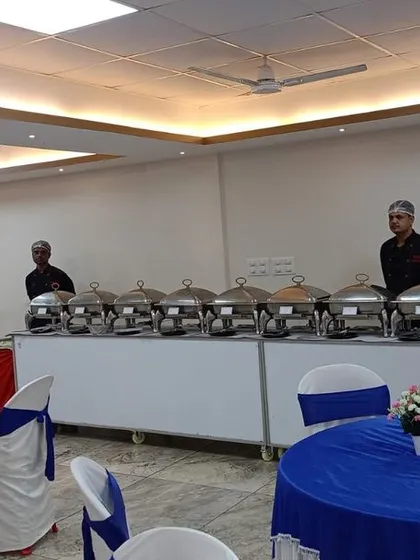 A clean and minimalist buffet setup in a party hall with blue and white themed decor, ready for a house party.