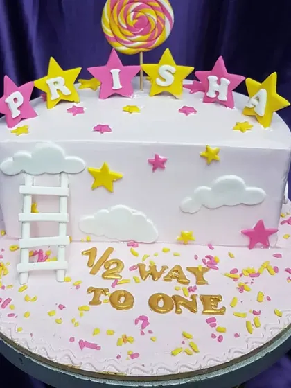 Celebrating a special milestone: halfway to one! This cute cake features a ladder climbing up to the stars, with a lollipop and personalized name blocks, perfect for a 6-month celebration.